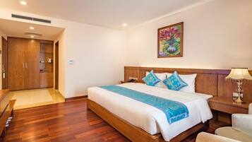 Habitación de hotel con cama de madera, mesita de noche, una silla, un cuadro en la pared y un armario de madera.