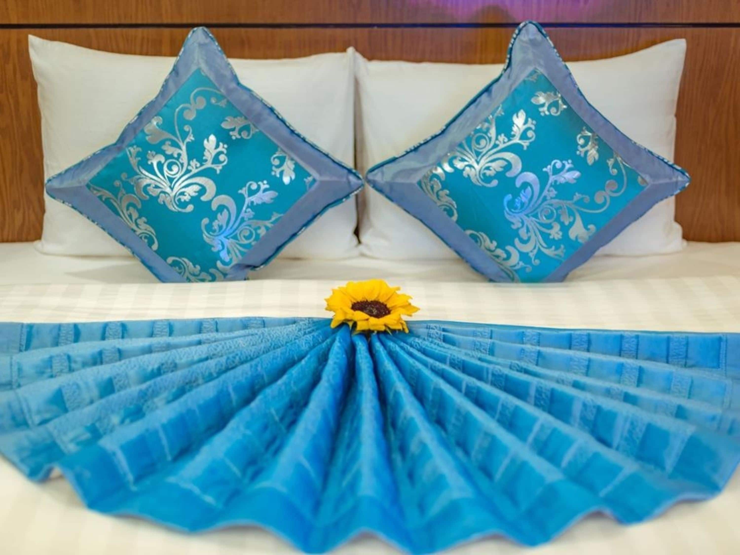 Una cama con dos almohadones decorativos y una colcha azul.