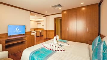 Habitación de hotel con cama, televisor, armario de madera y una zona de estar con mesa y sillas.