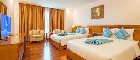Habitación de hotel con dos camas, televisión, escritorio y silla.