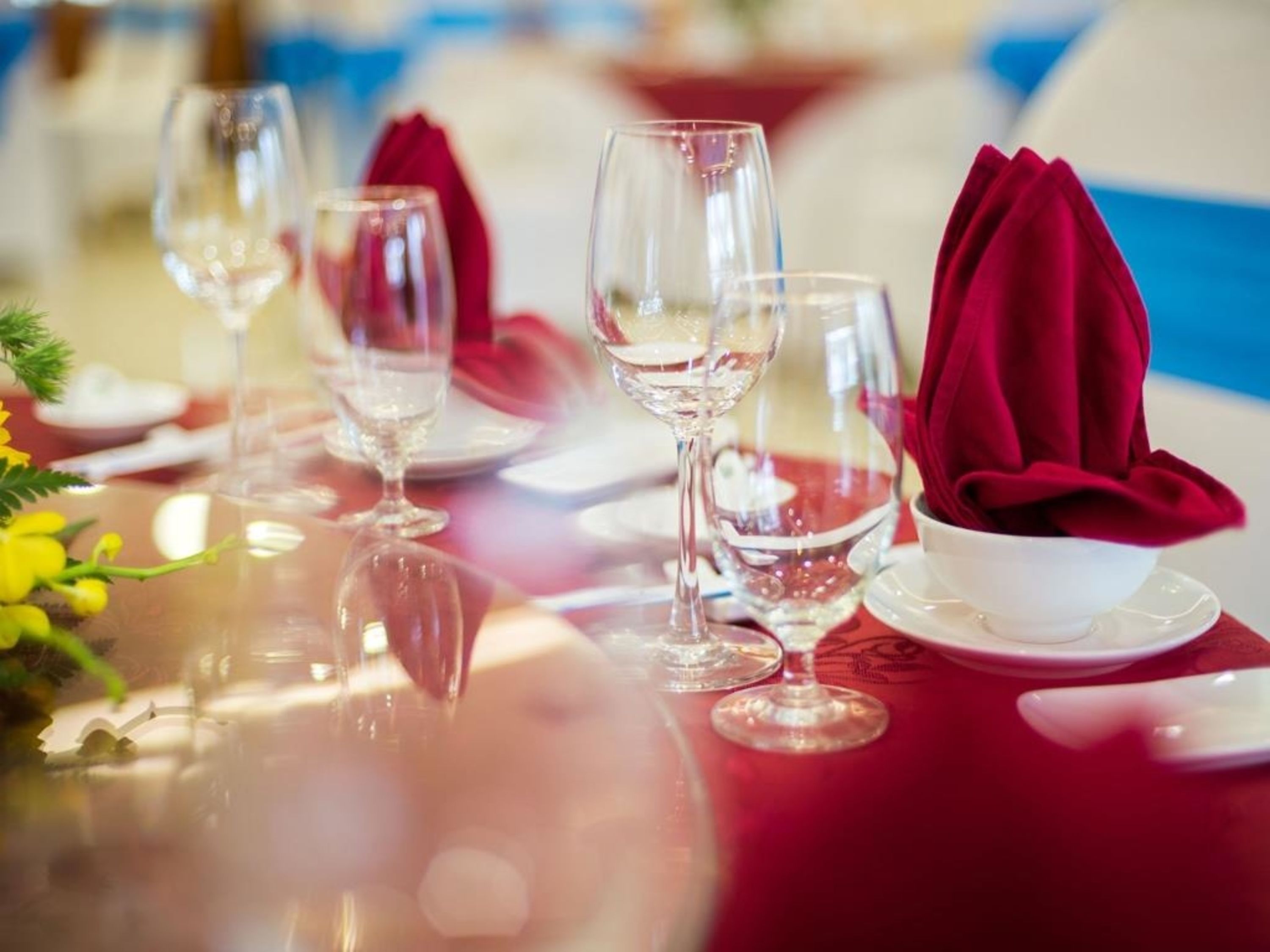 Una mesa lista para comer, con copas de vino, un bol y servilletas rojas.