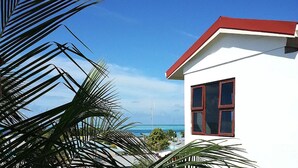 A white building with a red roof and a large window, overlooking a clear blue sky and a distant view of the ocean. - Tropic Tree Hotel Maldives (Gulhi)