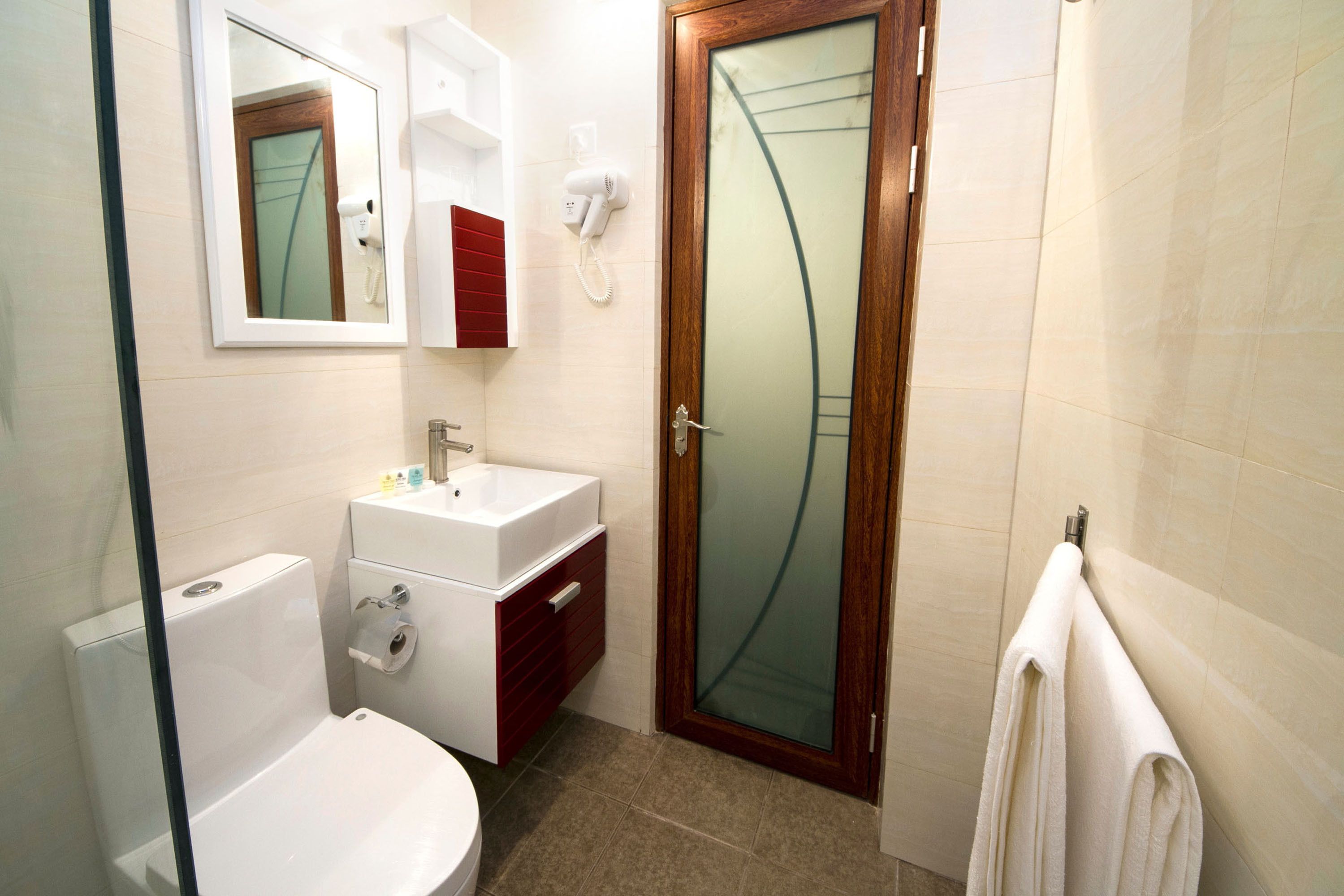 Un baño con inodoro, lavabo, espejo y ducha.