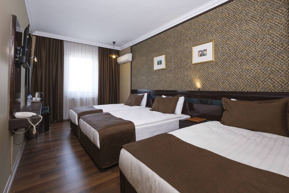 A hotel room with two beds, a desk with a telephone, and a mirror.