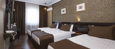 A hotel room with two beds, a desk with a telephone, and a mirror.