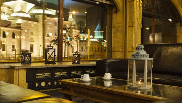 A cozy seating area with a table set for tea, a view of a historic building, and ornate architectural details. - Balikcilar Hotel (Konya)