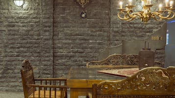 Un espace repas agrémenté d’un mur en pierre, d’un lustre et de meubles en bois richement décorés.