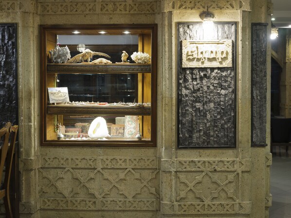 A shop with a display of jewelry and a stone wall with carved patterns. - Balikcilar Hotel (Konya)