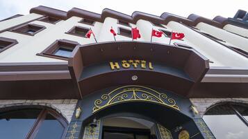 A hotel entrance with a sign reading "HOTEL" and multiple flags.