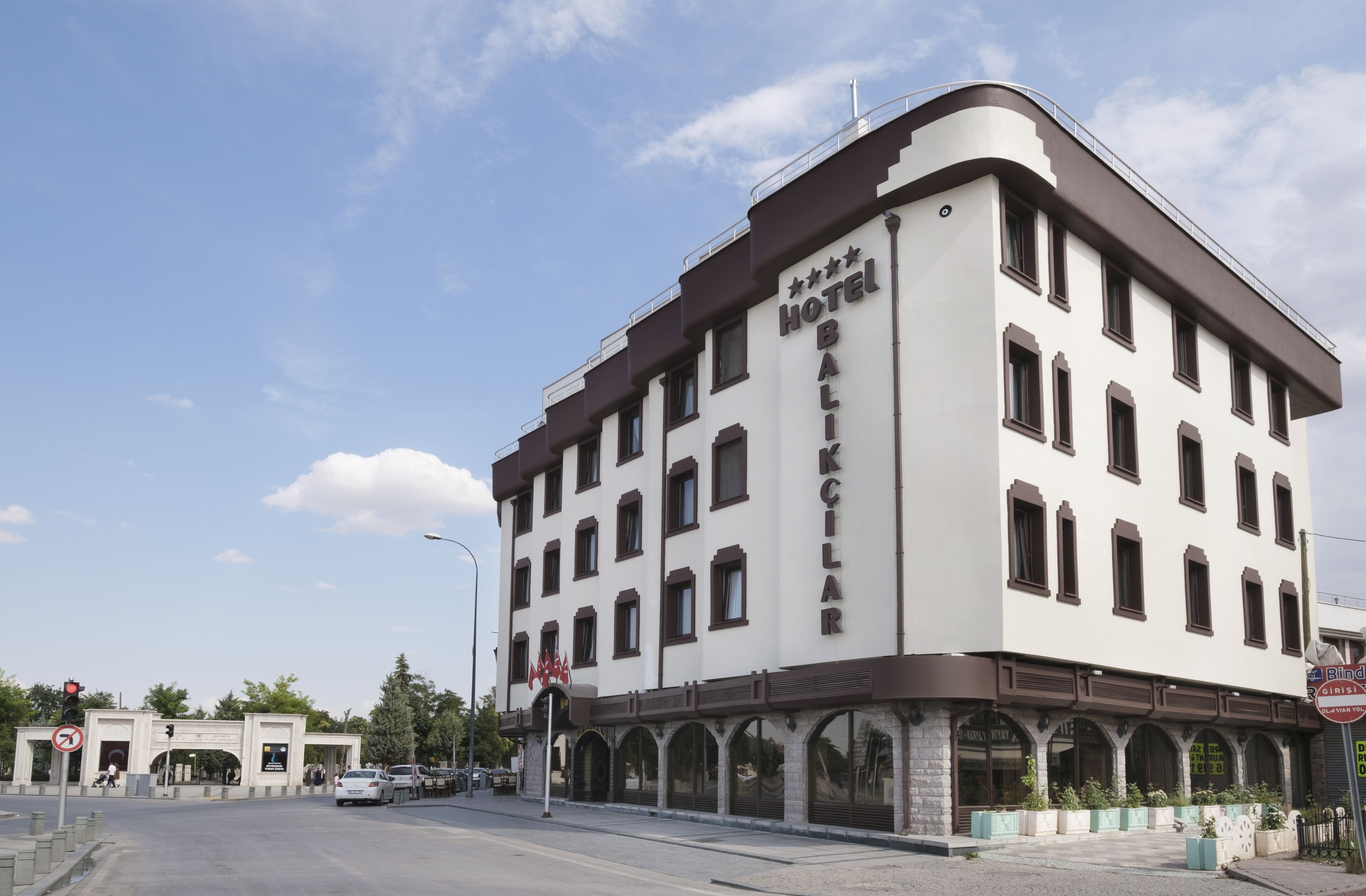 Un hotel de varios pisos con fachada blanca y detalles en marrón, que destaca por su entrada con un letrero.