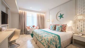 Una habitación de hotel moderna con cama, escritorio y silla, un ventanal con cortinas y un adorno de estrellas colgado en la pared.