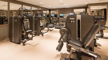 Ein Fitnessstudio mit verschiedenen Trainingsgeräten, Spiegeln und mehreren Fernsehbildschirmen.