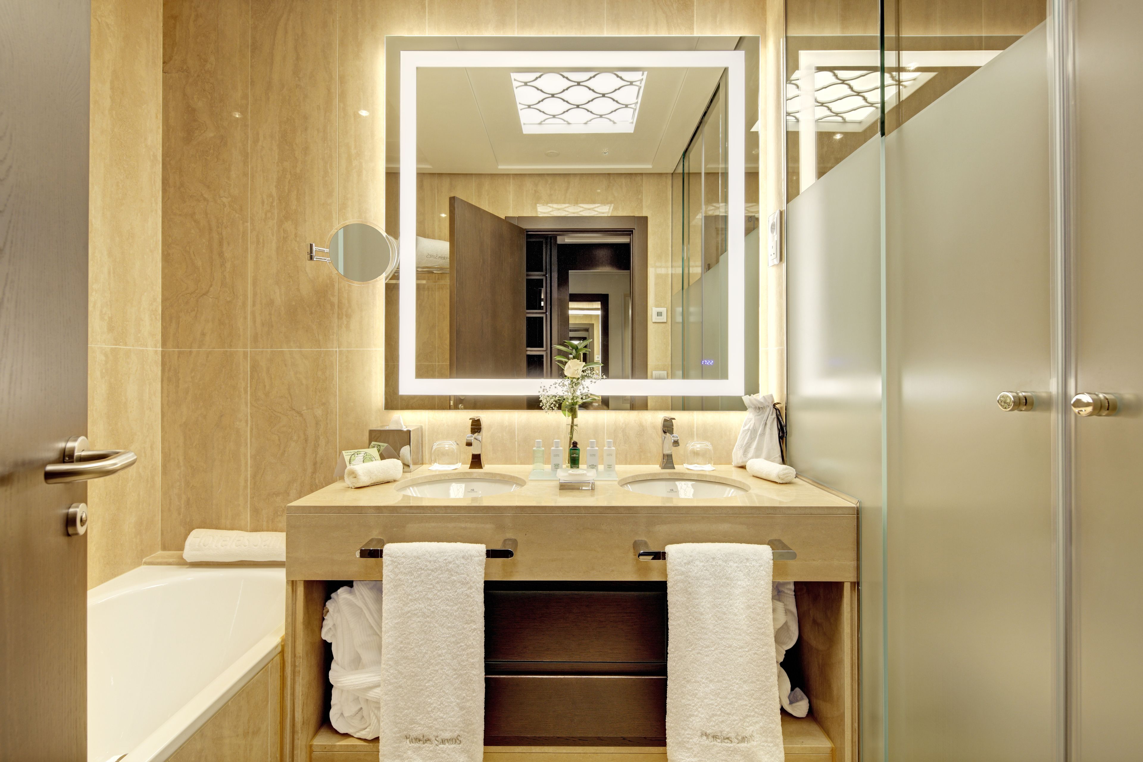 A modern bathroom with two sinks, a large mirror, and a glass shower enclosure.