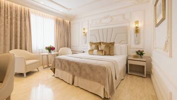 Een hotelkamer met een groot bed, een zithoek met een stoel en een klein tafeltje, en een nachtkastje met een lamp.