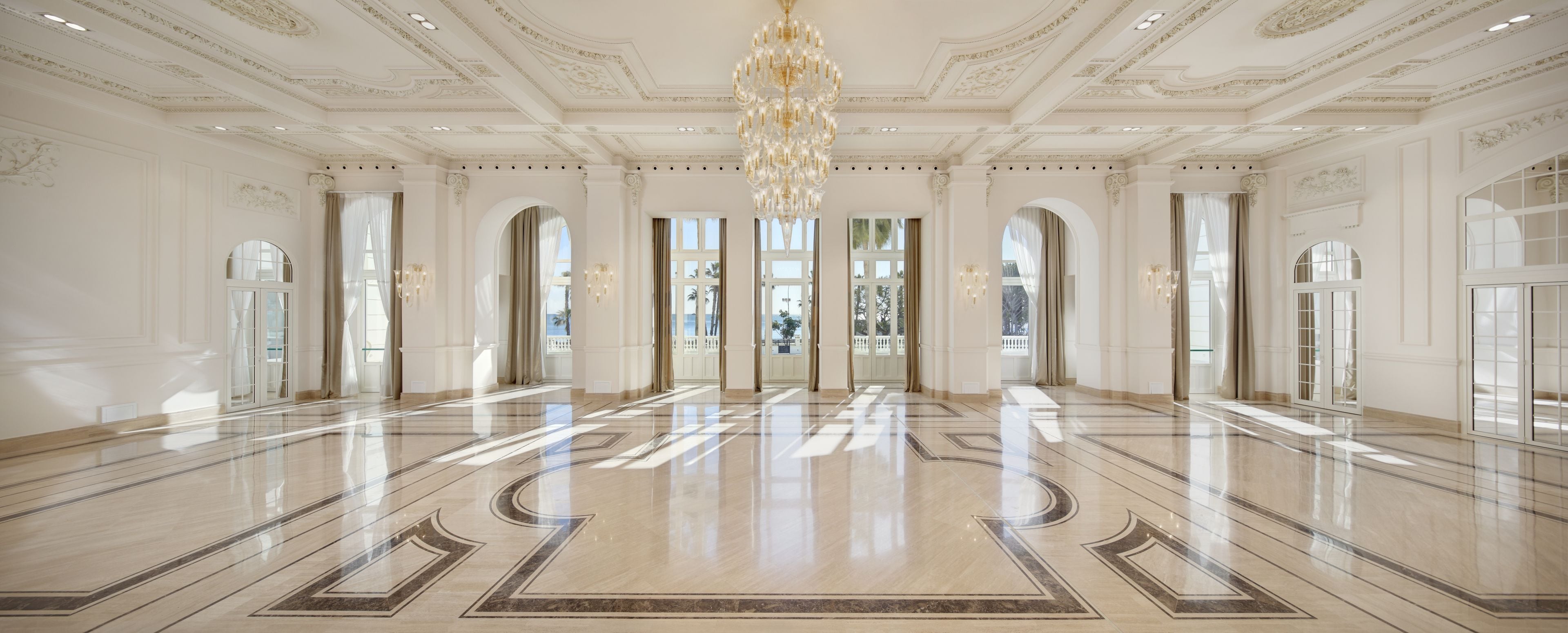 Eine geräumige Lobby mit poliertem Marmorboden, großen Fenstern und einem prächtigen Kronleuchter.