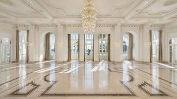 Eine geräumige Lobby mit poliertem Marmorboden, großen Fenstern und einem prächtigen Kronleuchter.