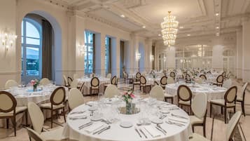 Un amplio salón de banquetes con mesas redondas, candelabros y una decoración elegante.
