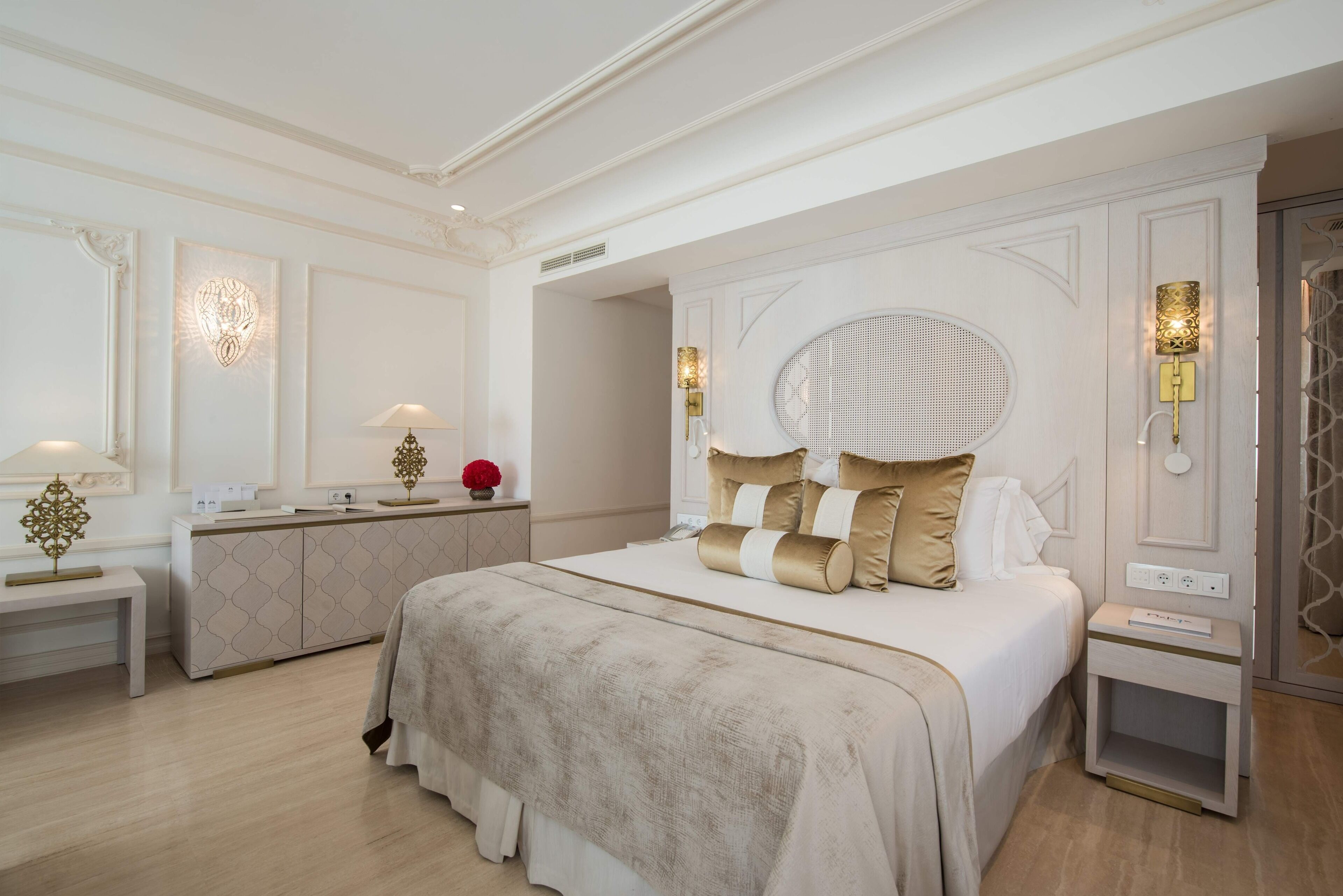 Un dormitorio amplio con una cama grande, una mesita de noche, un tocador y un espejo.