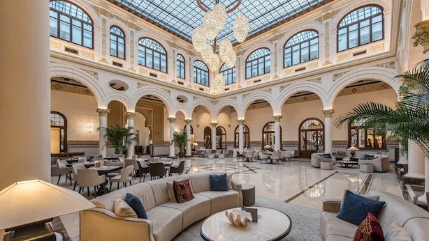 A spacious lobby with a high ceiling, large windows, and a central seating area with sofas and a coffee table. - Gran Hotel Miramar GL (Málaga)