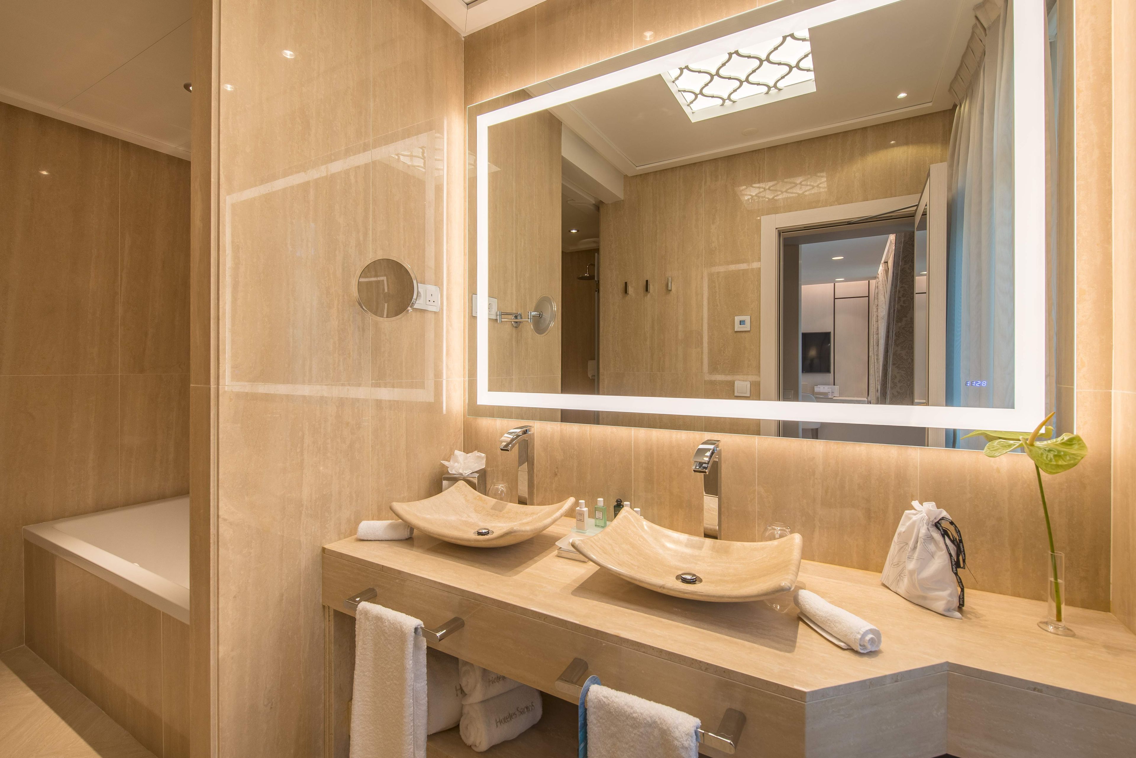 A modern bathroom with two vessel sinks, a large mirror, and a shower area.
