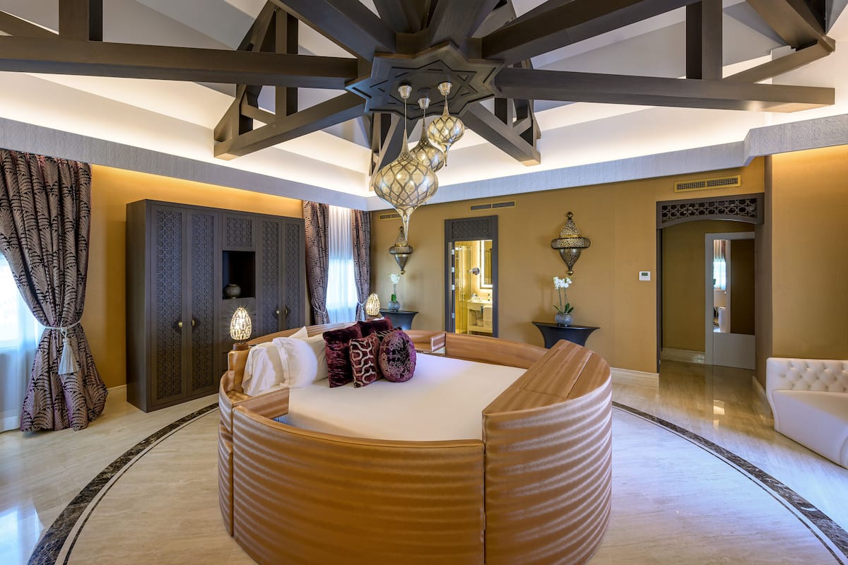 Un dormitorio lujoso con una cama grande, techo de madera y un candelabro.