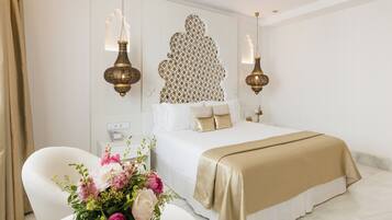 Ein Hotelzimmer mit einem großen Bett, einem Nachttisch mit Blumenvase und zwei Wandlampen.