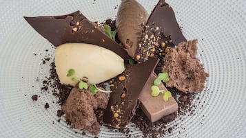 A dessert with chocolate pieces, a scoop of ice cream, and a piece of cake on a textured plate.