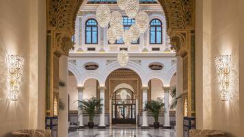 Un lobby ornamentado con un arco imponente, candelabros y columnas.