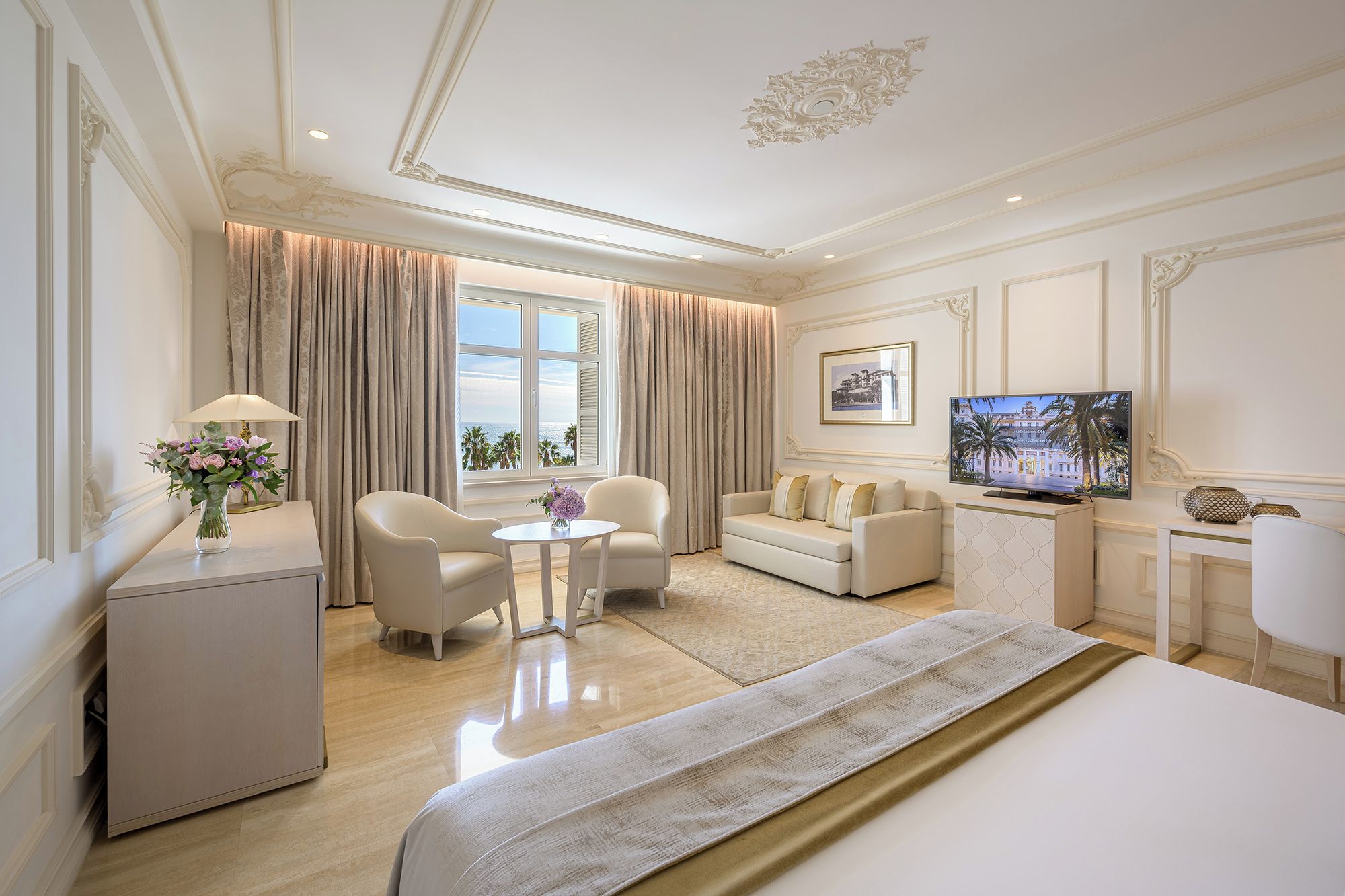 Una habitación de hotel con una cama, televisor, sofá, escritorio y una silla.