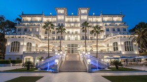 A grand hotel with multiple floors, a central staircase, and outdoor seating areas. - Gran Hotel Miramar GL (Málaga)