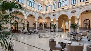 A spacious lobby with high ceilings, large windows, and elegant chandeliers. - Gran Hotel Miramar GL (Málaga)