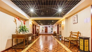 A hotel hallway with a patterned floor, wooden furniture, and a ceiling with a grid design. - Xian Ancient City Youth Hostel (Xi'an)
