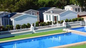 Una piscina con una valla blanca y una hilera de casas móviles al fondo.