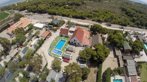 Vista aérea de una zona residencial costera con piscina, casas y una carretera.