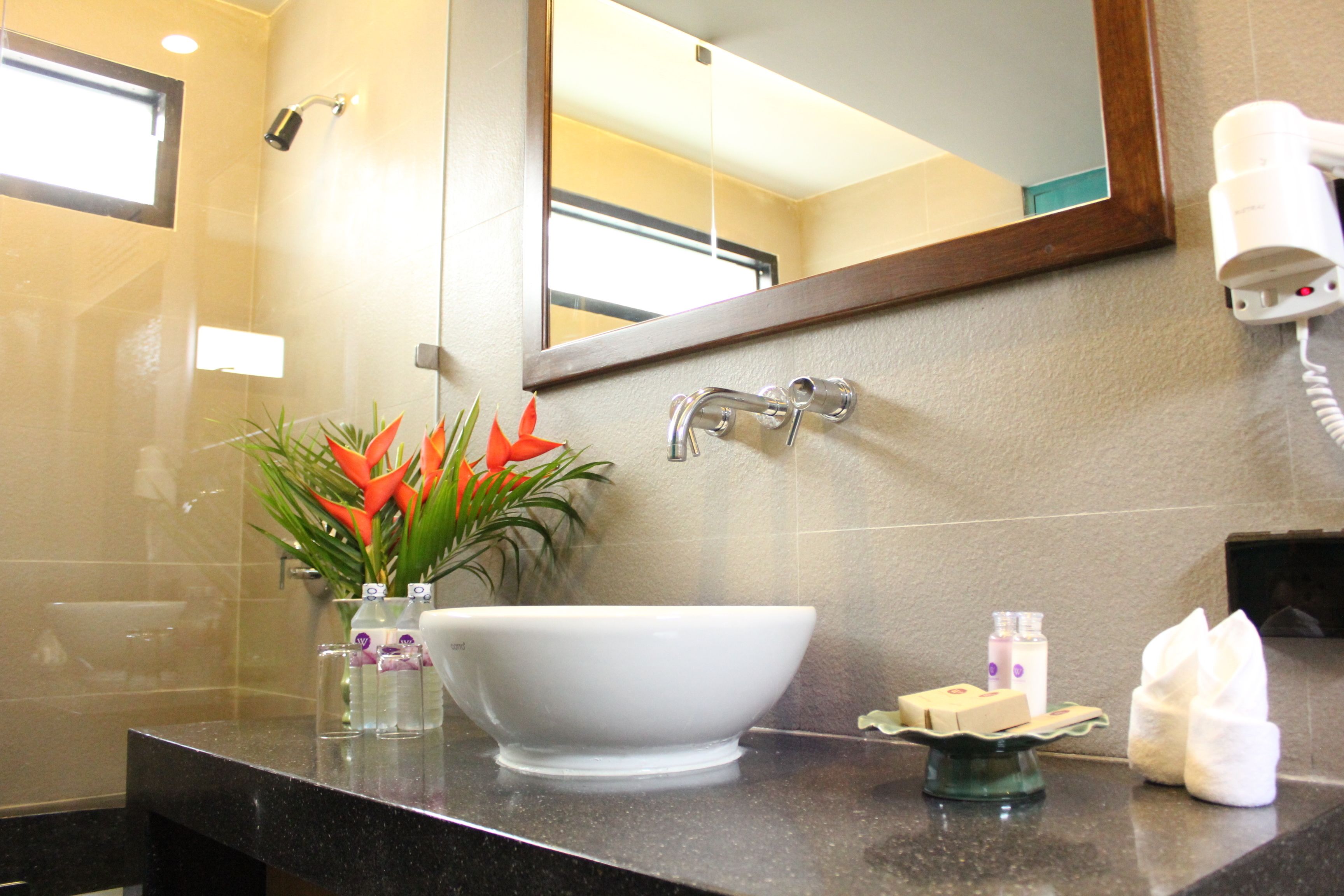 Une salle de bain avec un lavabo blanc, un miroir, un sèche-cheveux et des articles de toilette.