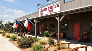 HH Creek Inn -niminen hotelli, jossa on katettu ulkoalue, lippuja ja punainen ovi.