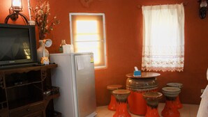 A compact living space with a television, refrigerator, and a small table with stools.
