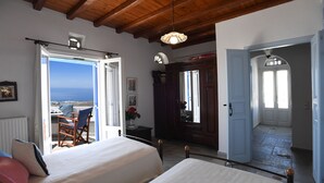 Een slaapkamer met een bed, een stoel en uitzicht op zee.