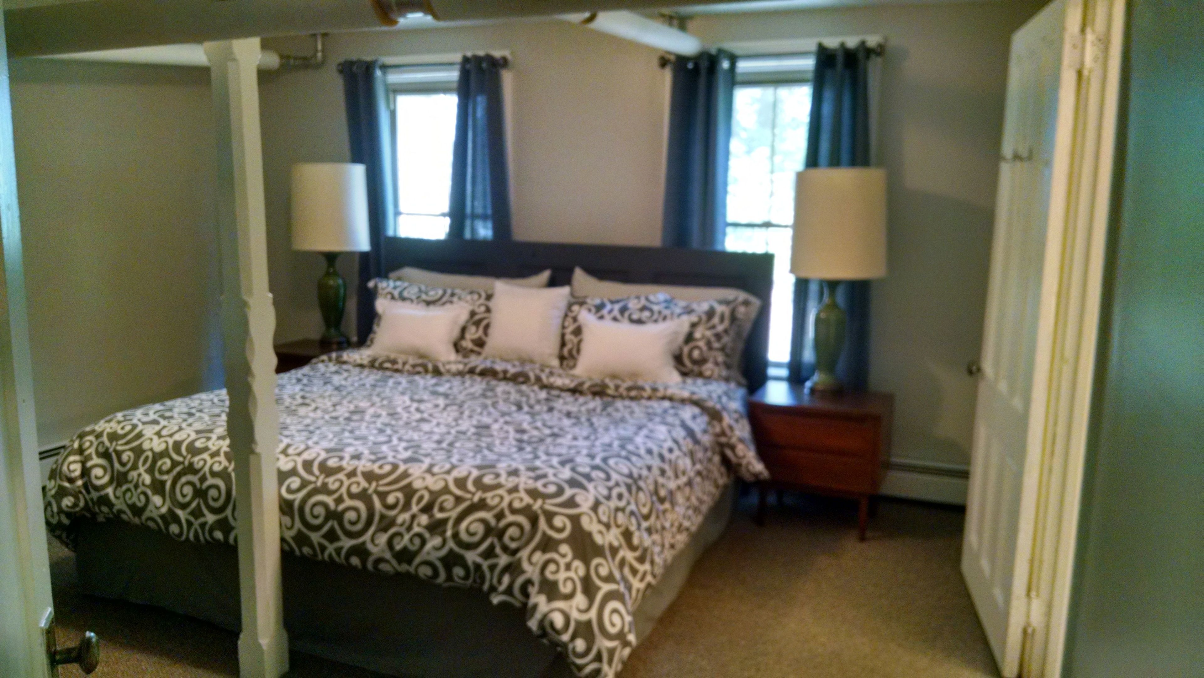 A bedroom with a four-poster bed, two bedside lamps, and a nightstand.