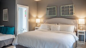 A bedroom with a large bed, two bedside tables, a nightstand, a door, and a window with curtains. - River Run Bed and Breakfast (Fleischmanns)