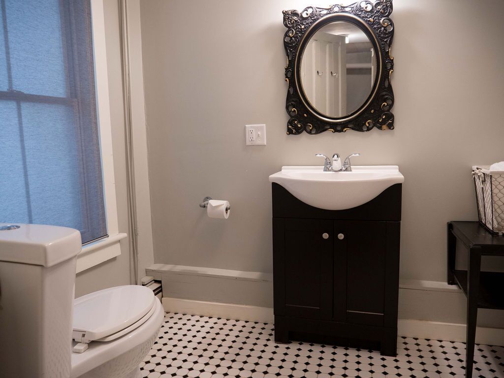 A bathroom with a toilet, sink, and mirror.