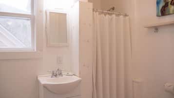 A bathroom with a white sink, a mirror, a shower curtain, and a painting of a cow on the wall.