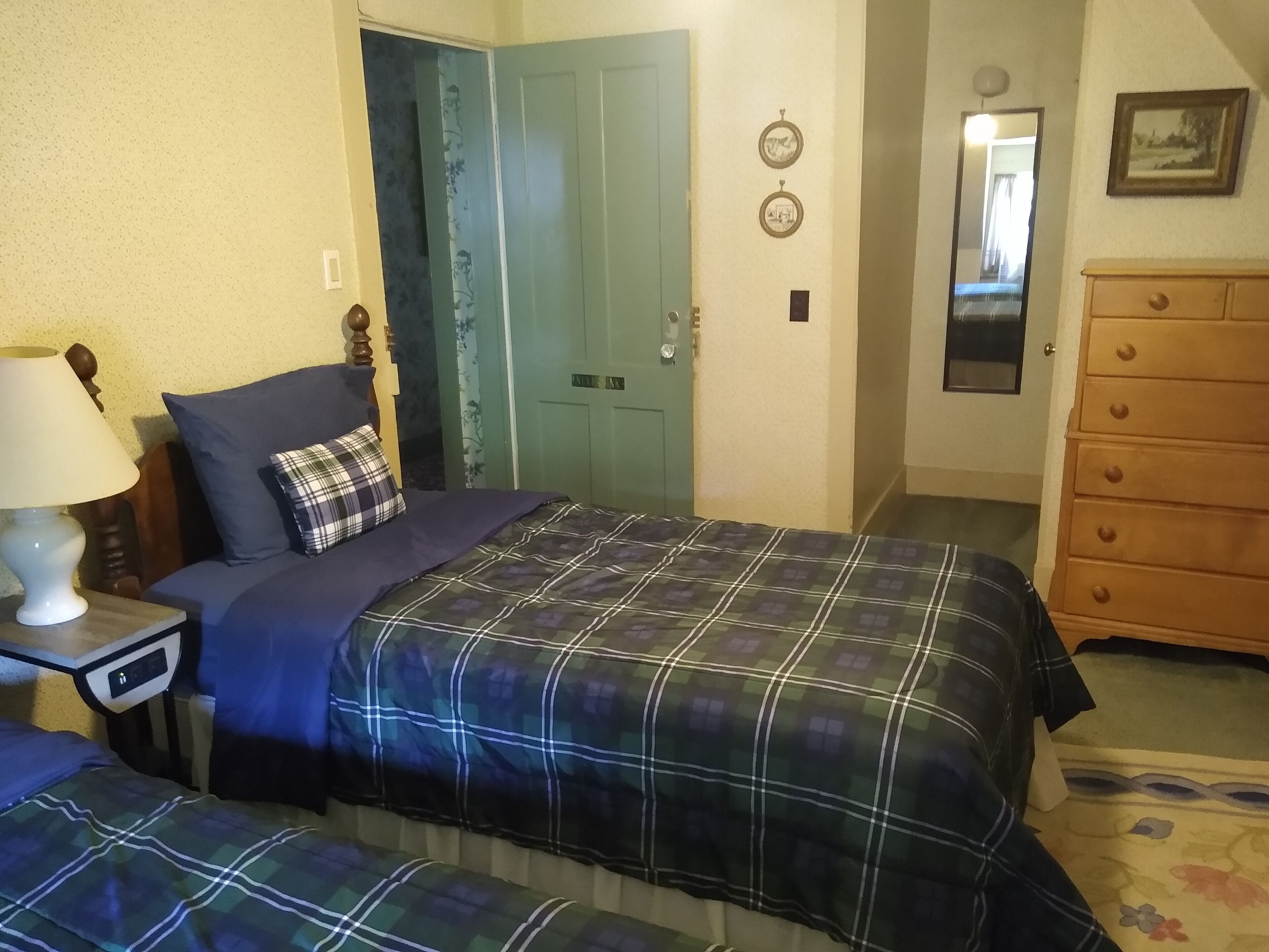 Une chambre à coucher avec un lit, une commode, une table de chevet et une porte.