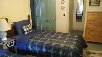 Une chambre à coucher avec un lit, une commode, une table de chevet et une porte.