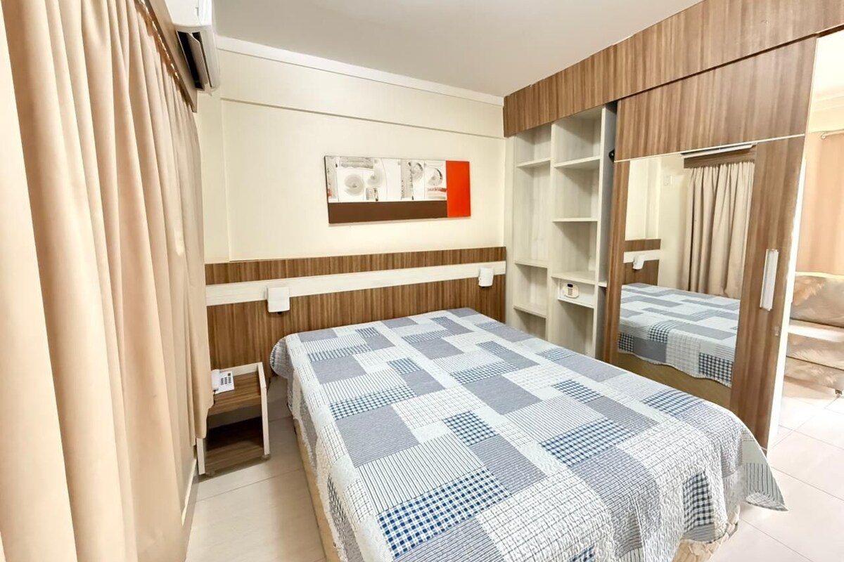 Un dormitorio con cama, armario, espejo y aire acondicionado instalado en la pared.