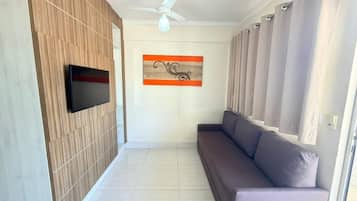 Un salon moderne doté d’un téléviseur à écran plat, d’un ventilateur de plafond, d’un canapé et d’un élément décoratif mural.