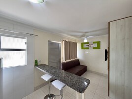 Uma cozinha moderna com bancada de granito, um banqueta, um sofá de couro marrom e um ventilador de teto.