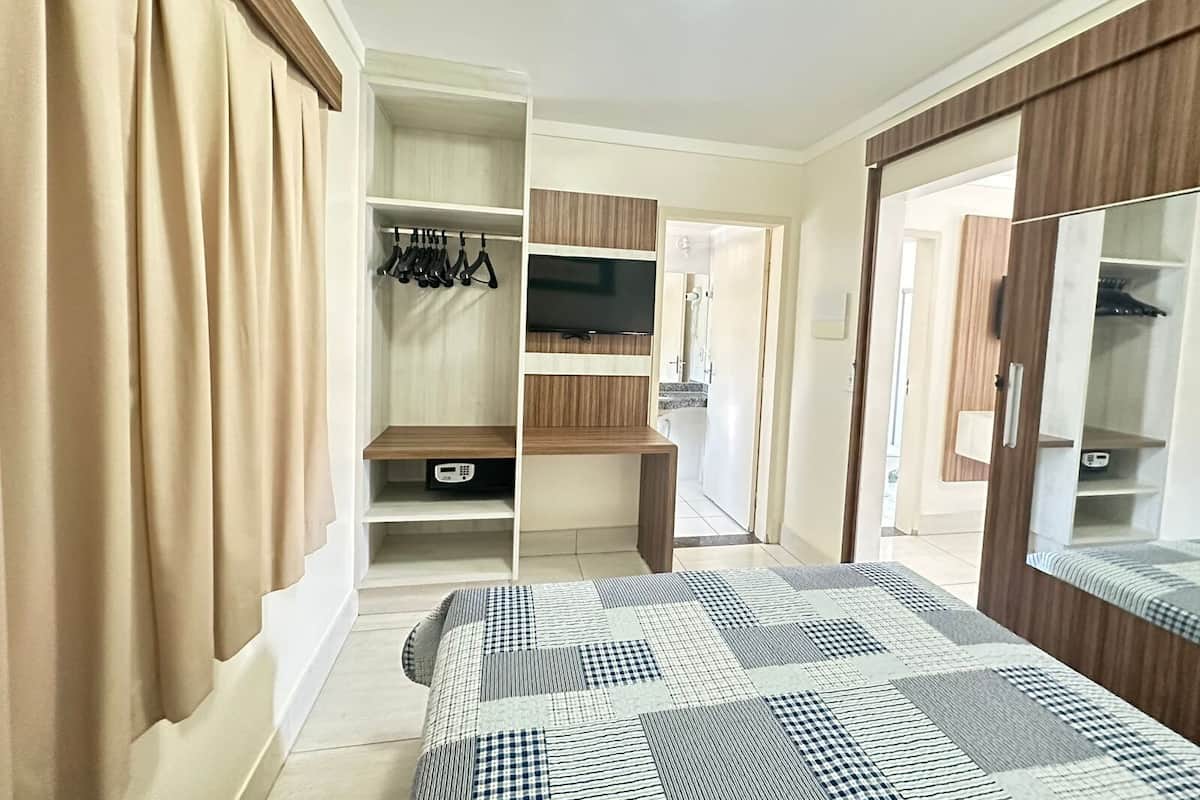 A bedroom with a bed, wardrobe, TV, and a bathroom door.