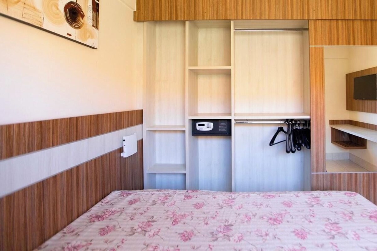 Un dormitorio con cama, armario y televisor montado en la pared.