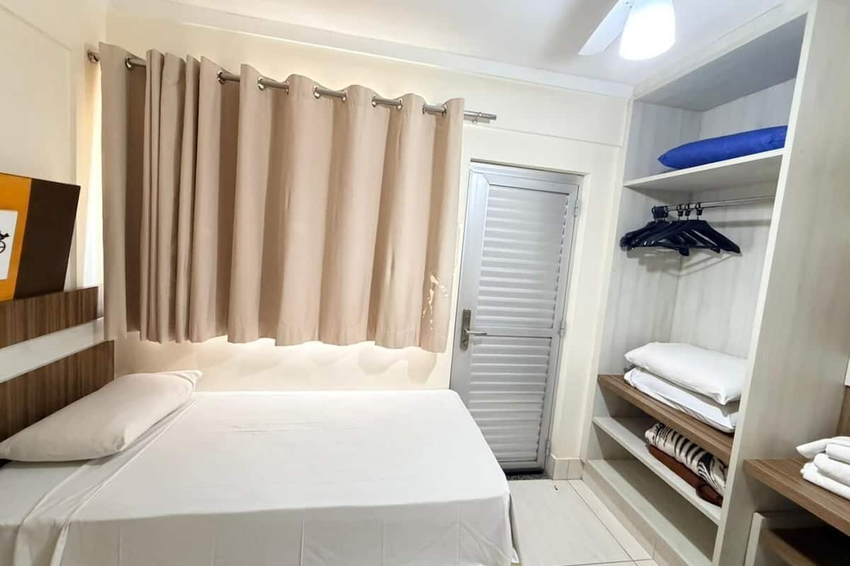 A hotel room with a bed, a wardrobe, and a door.